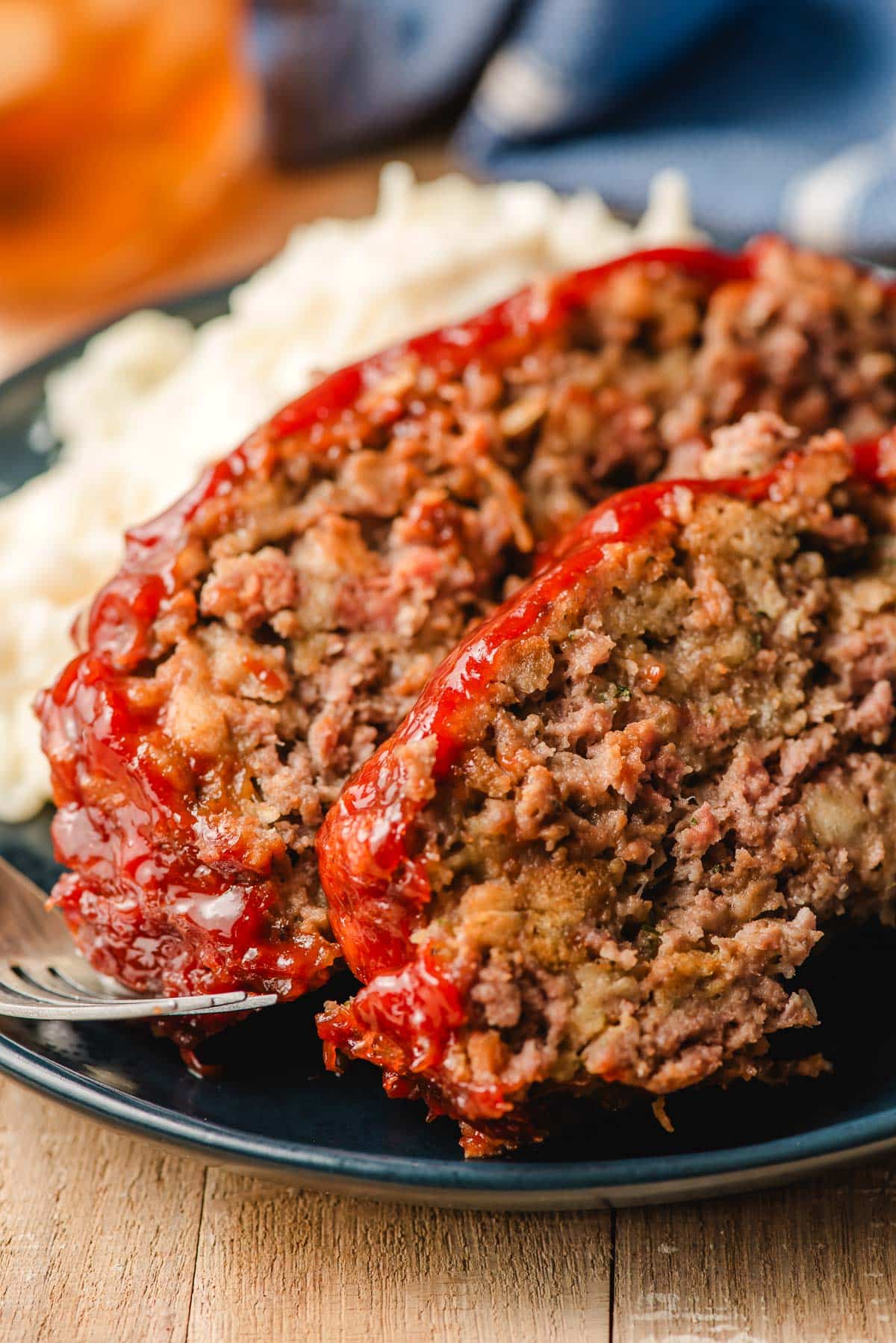 Two slices of stove top stuffing meatloaf with mashed potatoes on a plate.