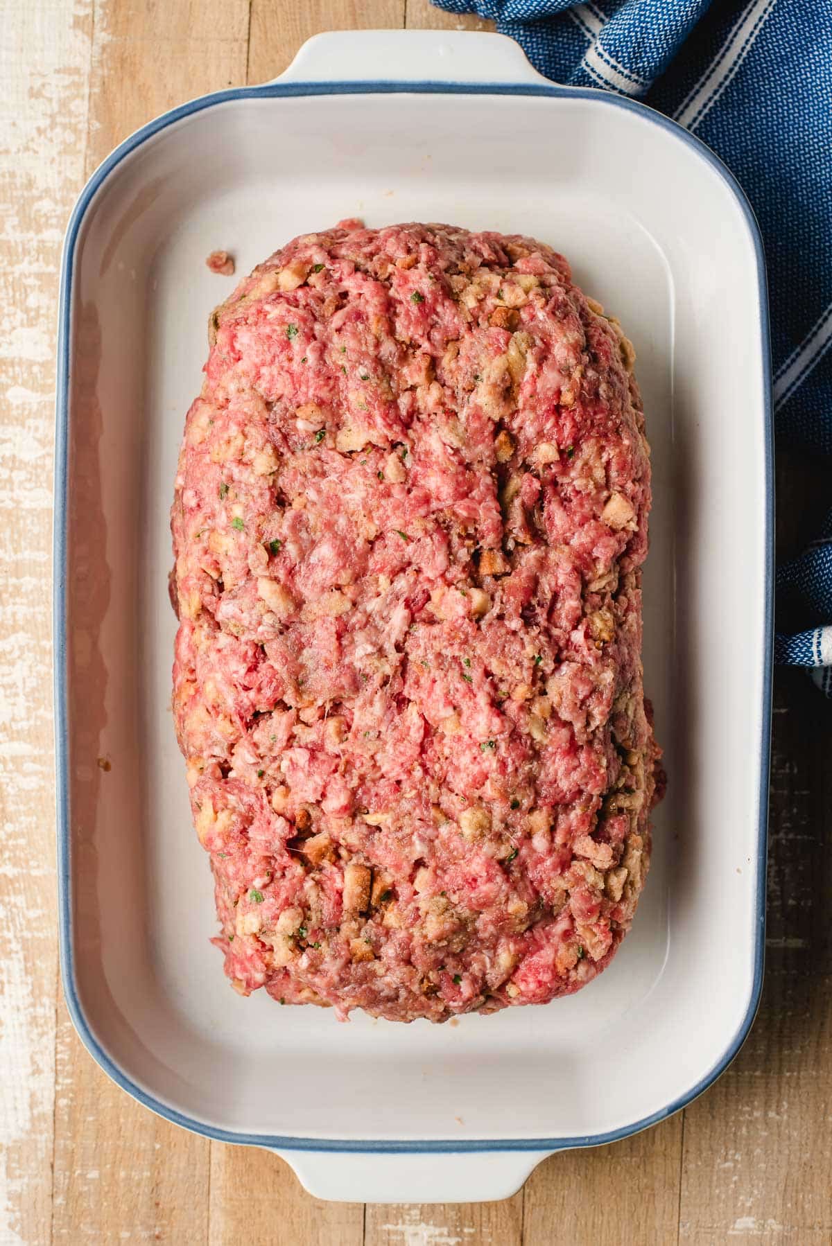Unbaked meatloaf with stuffing in a casserole dish.