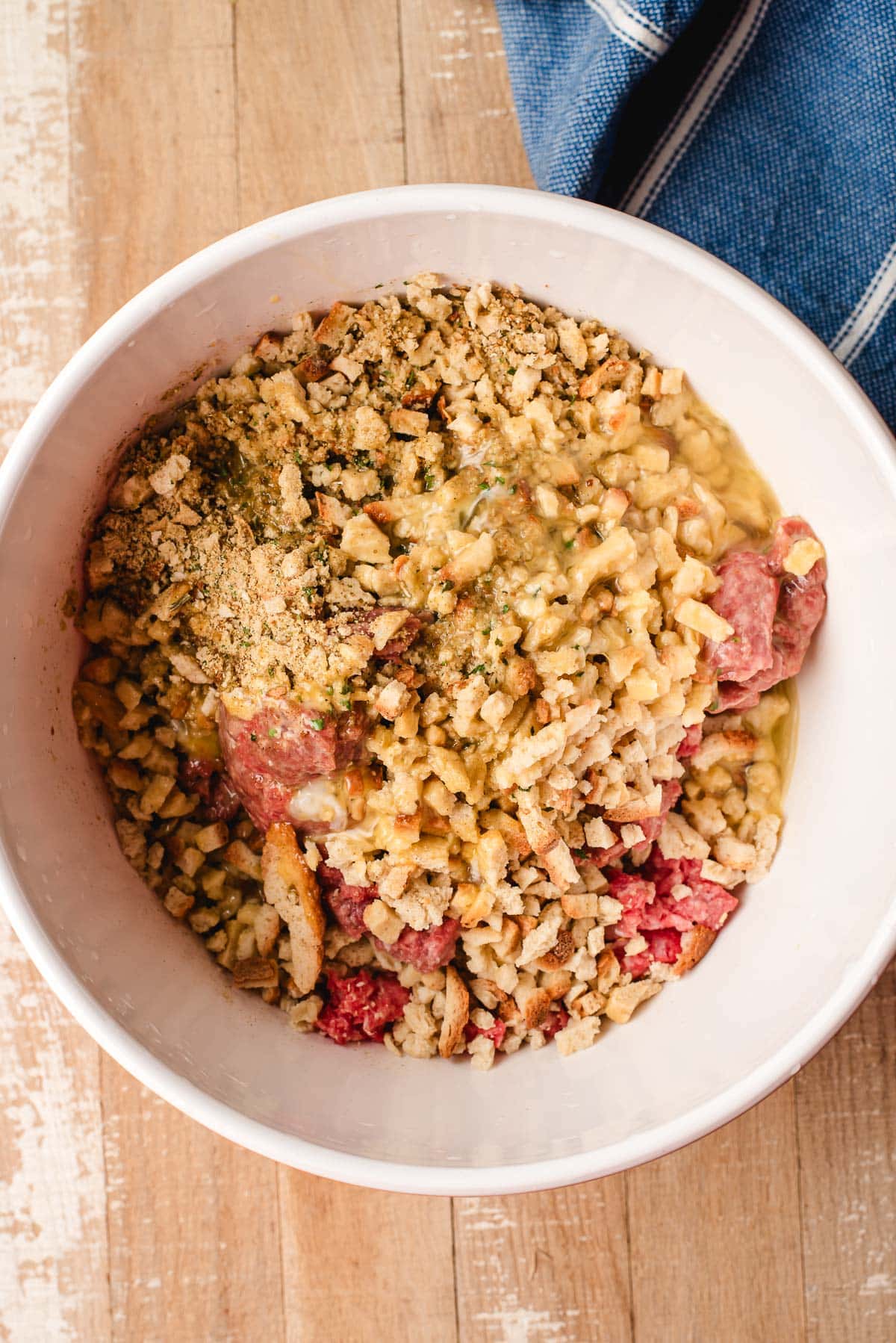 Stove top stuffing poured over ground beef in a bowl.