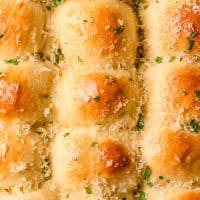 Dinner rolls topped with garlic butter, parmesan, and parsley.
