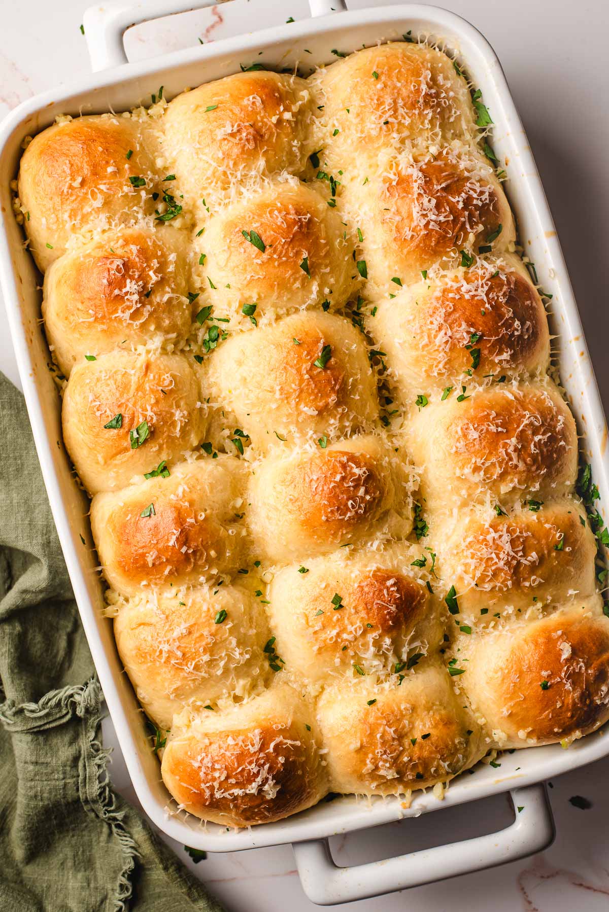Garlic butter dinner rolls in a white casserole dish.