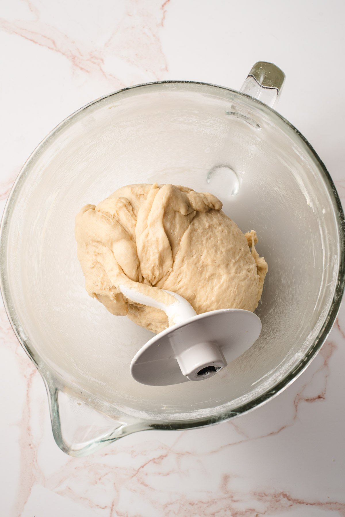 Bread dough after being kneaded with the dough hook in a glass mixing bowl