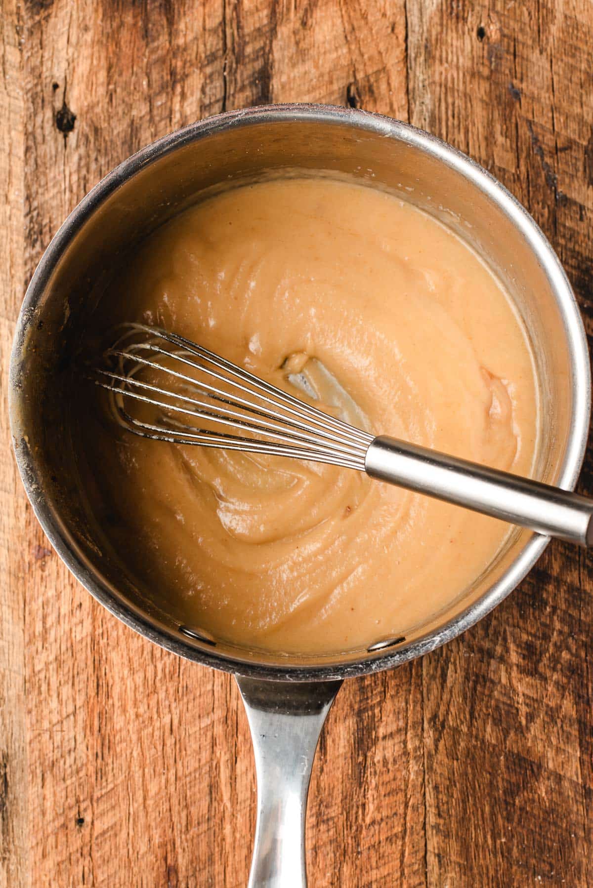 Whisking broth into a roux in a sauce pan.