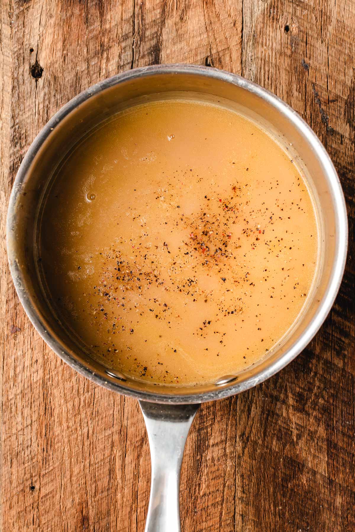 Homemade gravy in a sauce pan with salt and pepper.