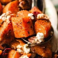Spoon holding cubed sweet potatoes with goat cheese.