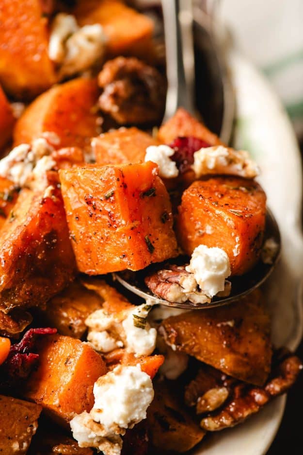 Spoon holding cubed sweet potatoes with goat cheese.
