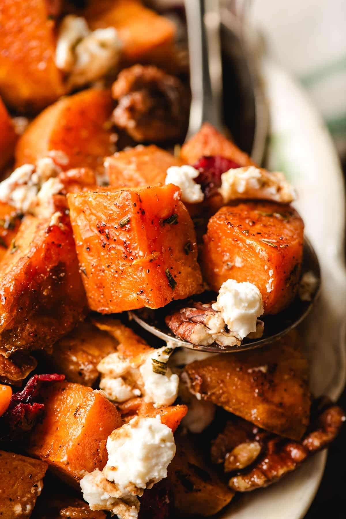 Spoon holding cubed sweet potatoes with goat cheese.