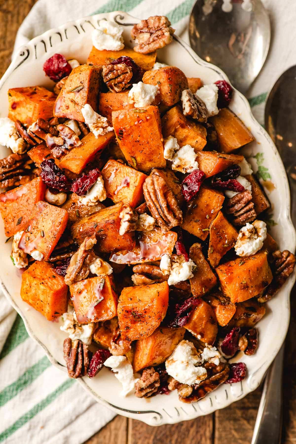 Roasted sweet potatoes with goat cheese, pecans, and dried cranberries in a serving bowl.