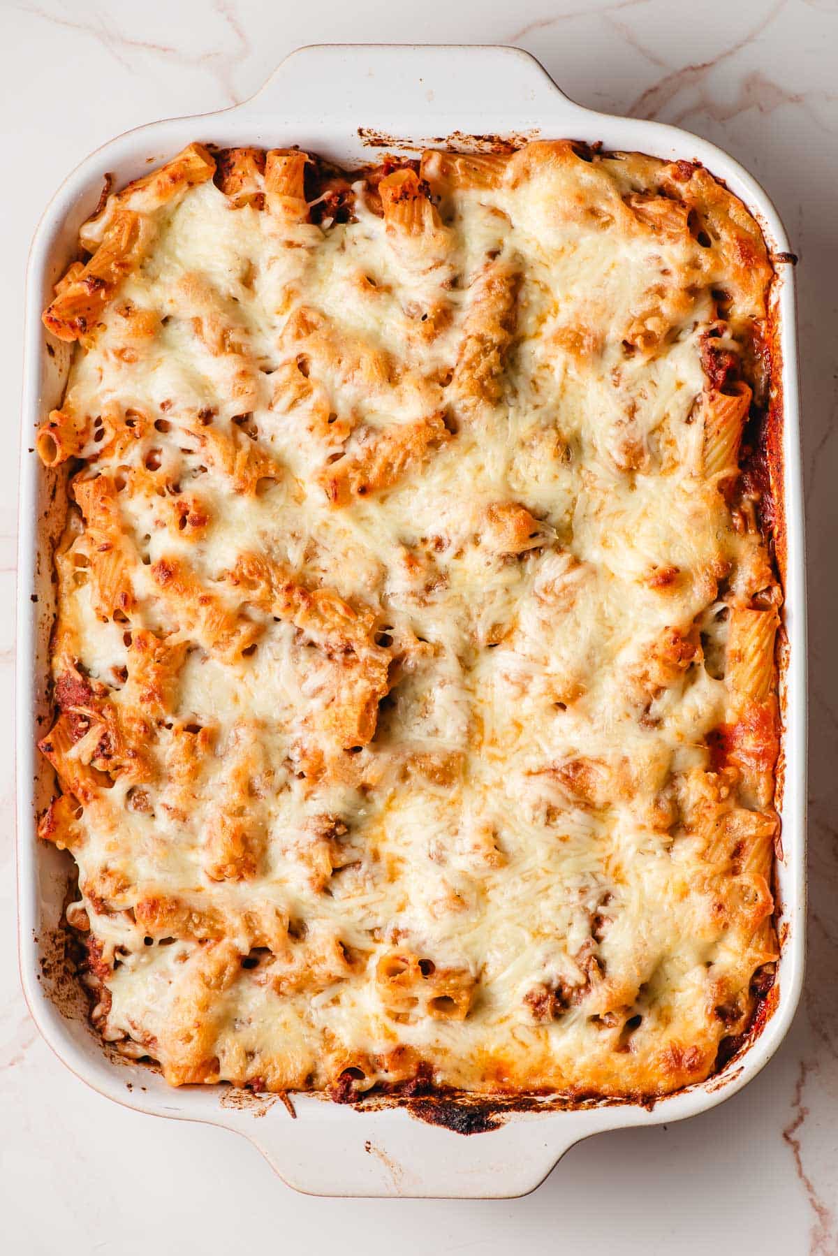 Cheesy baked rigatoni in a casserole dish.