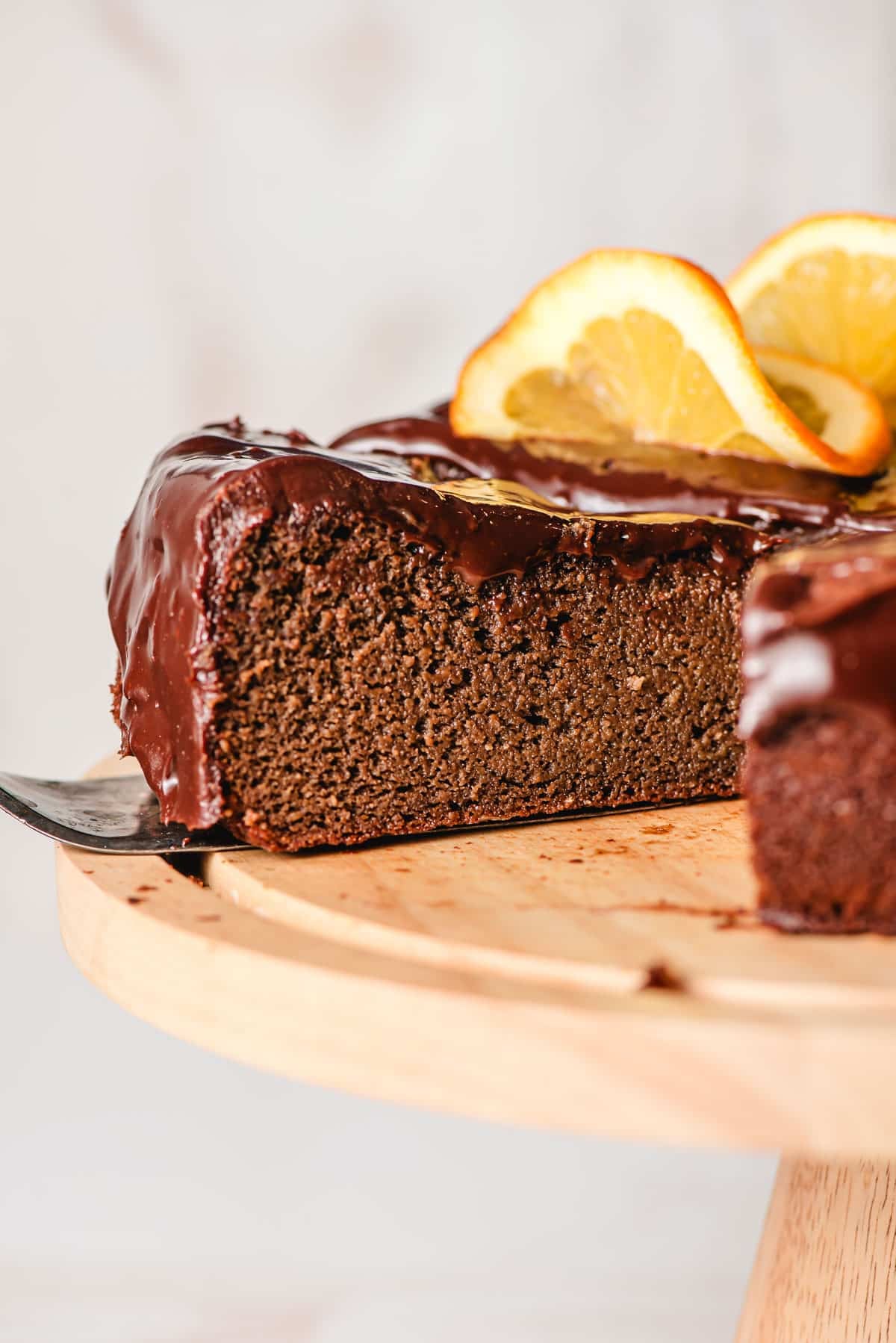 a slice of cake showing the fudgy texture of the center topped with chocolate ganache.