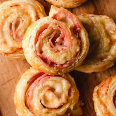Ham and cheese puff pastry bites on a wooden cutting board.