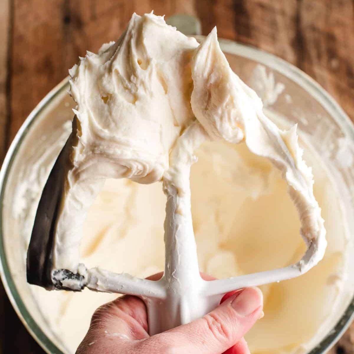 Cream cheese frosting on the beaters of an electric mixer.