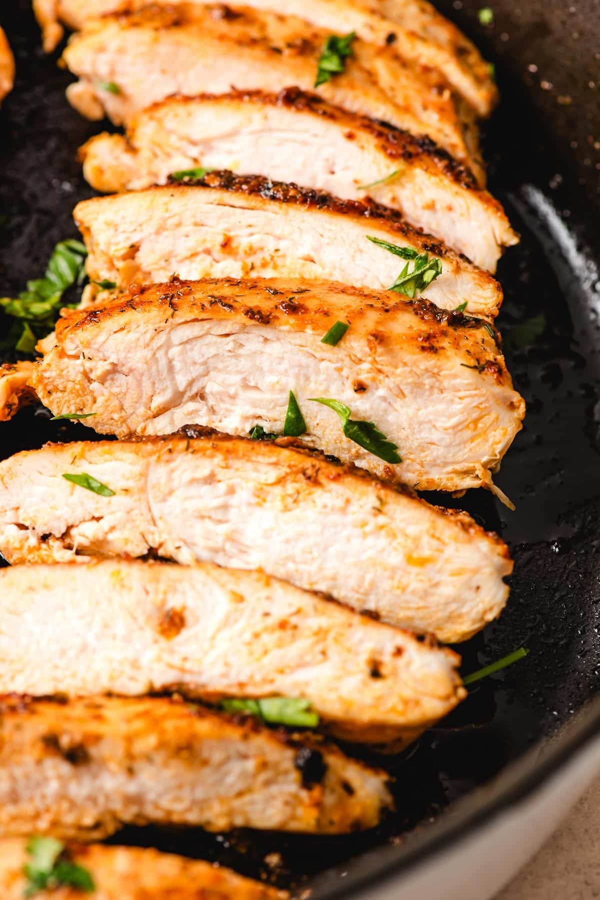 Chicken breast sliced in a cast iron skillet.