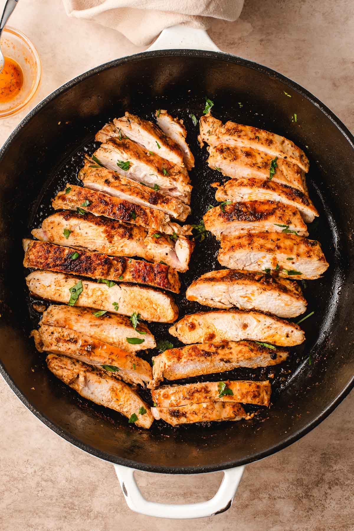 Two chicken breasts sliced in a cast iron skillet.