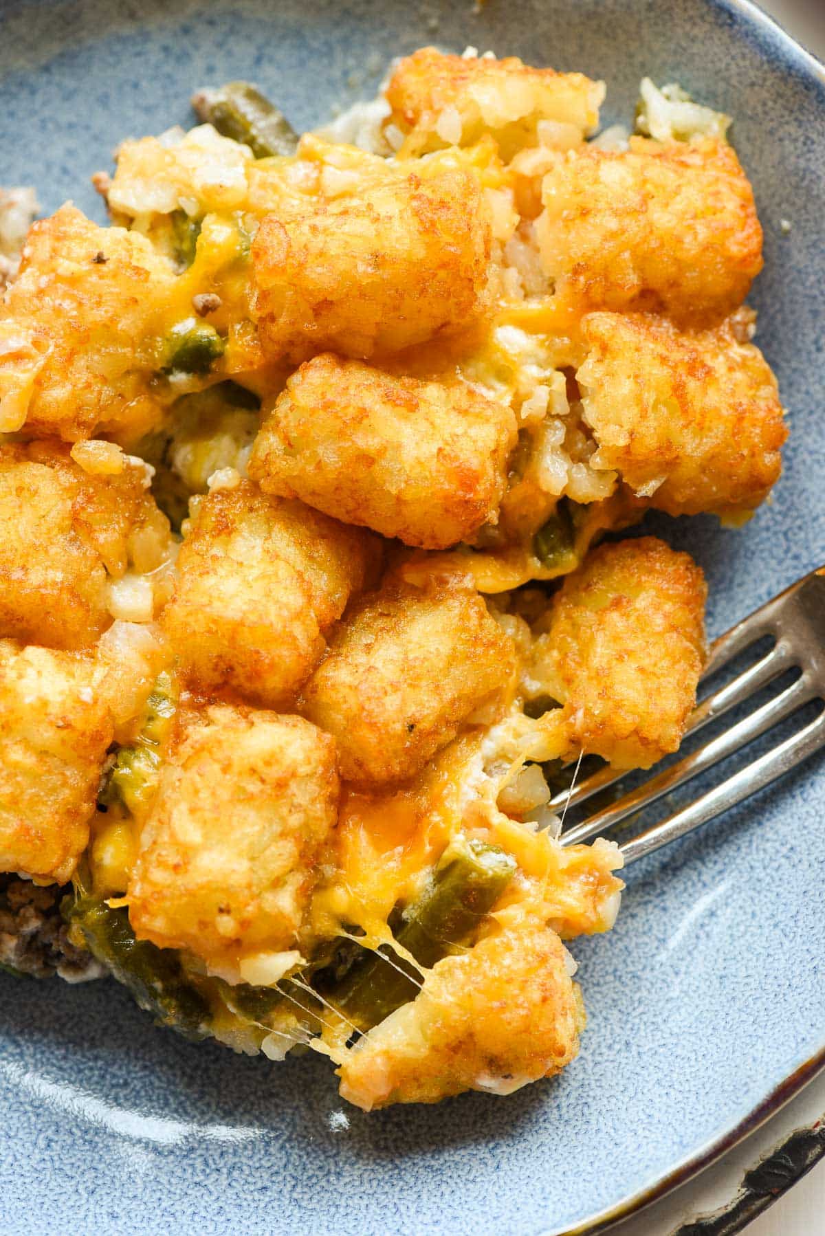 a close up of tater tot casserole served in a blue dish.