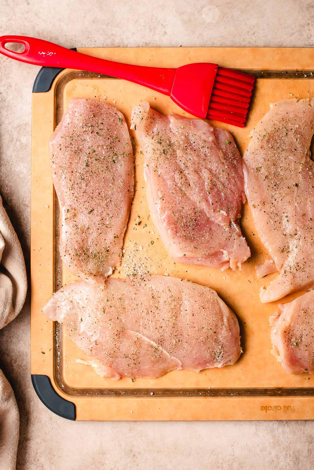 seasoning raw chicken to prepare it for dredging.