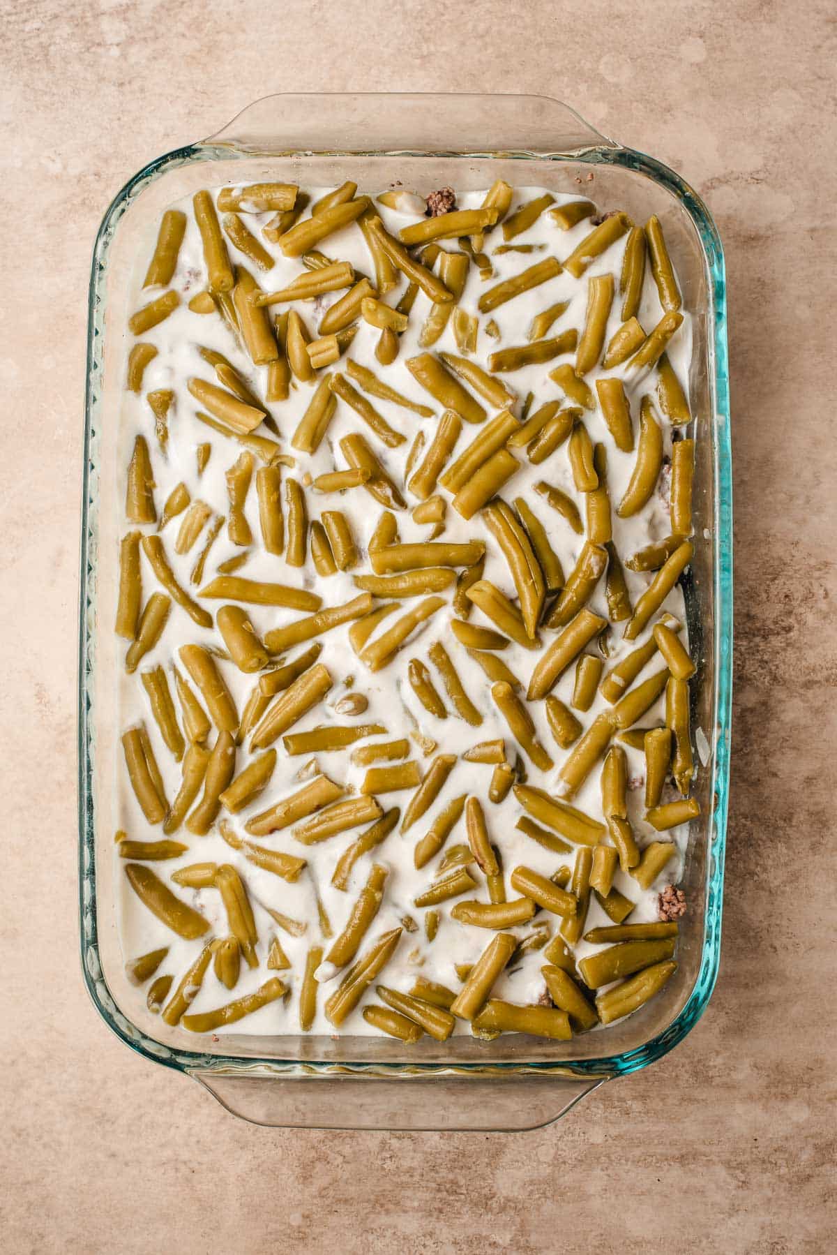 the milk mixture and green beans poured into the casserole dish atop the ground beef