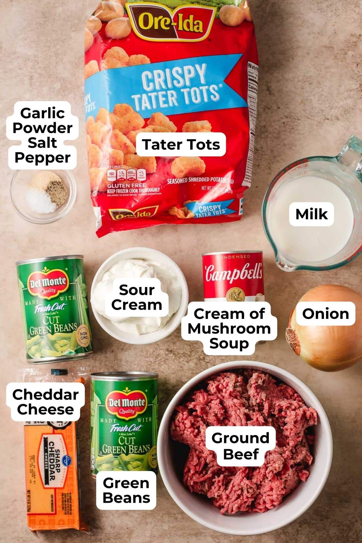 tater tot casserole ingredients on a counter including ground beef, tater tots, green beans, seasonings, milk, and egg.