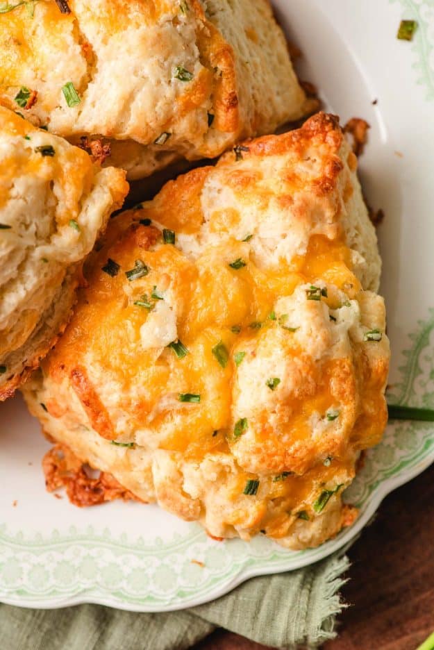Overhead shot of a cheddar chive scone on a plate with melty cheese on top.
