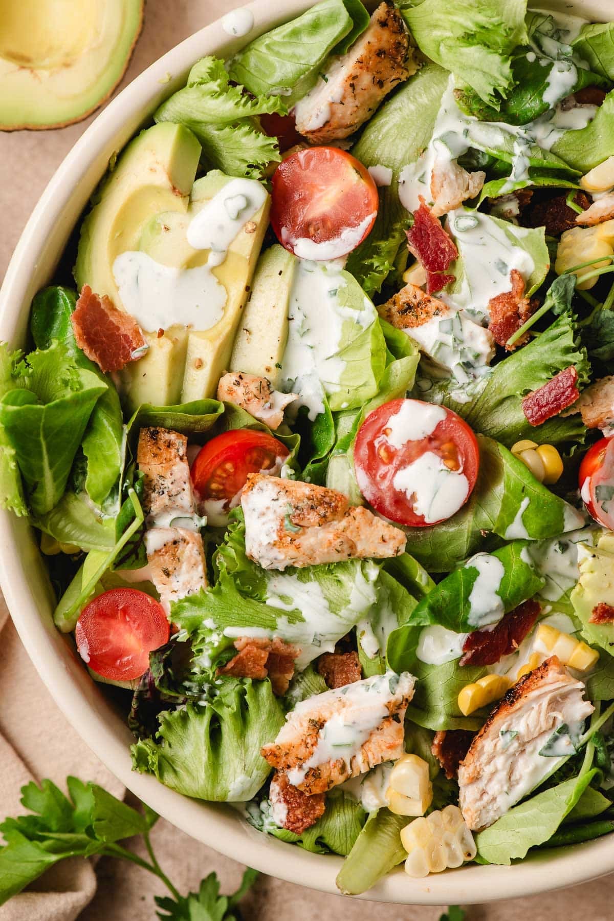 Green salad with tomatoes, sliced avocado, and cilantro ranch dressing.
