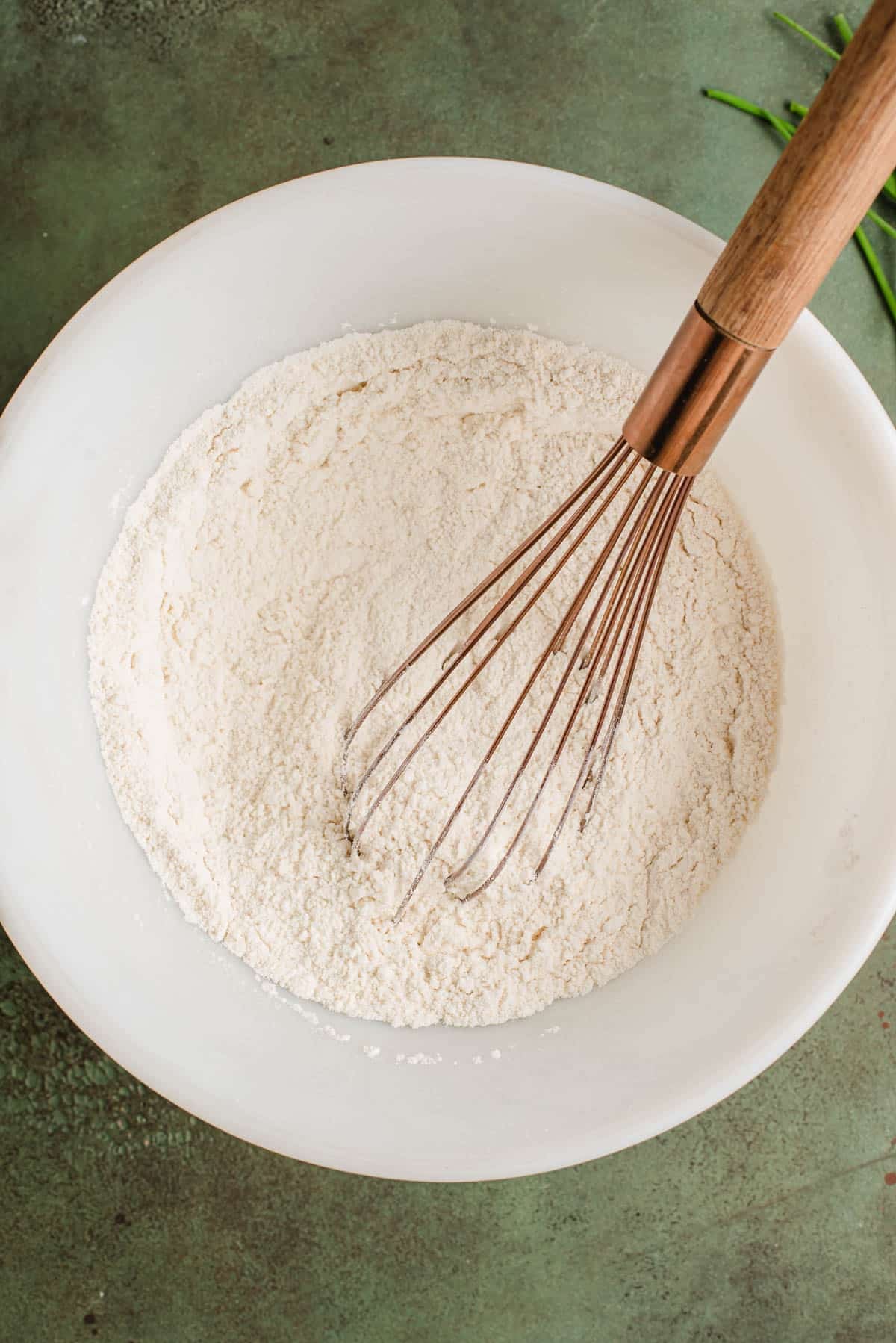 Whisking together the dry ingredients for cheddar chives scones in a bowl.