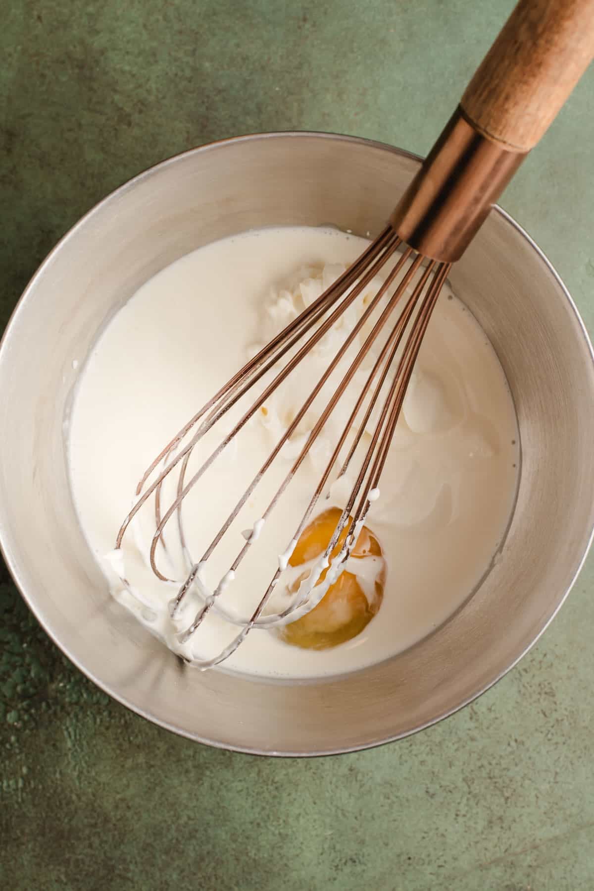 Whisking together the wet ingredients for cheddar chive scones in a large bowl.