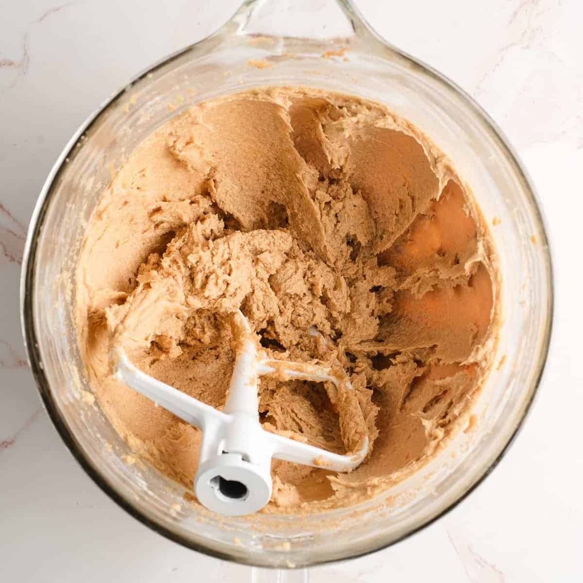 Butter, brown sugar, eggs, and vanilla beated together in a glass mixing bowl.